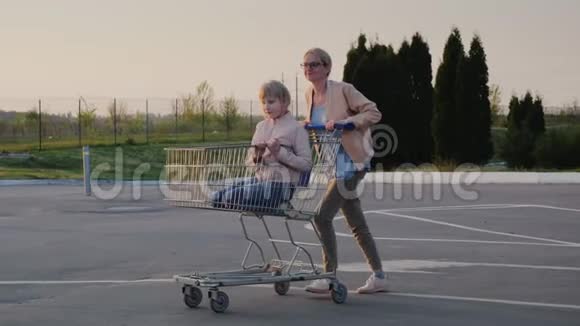 女人在超市的停车场里玩把孩子卷进购物车视频的预览图