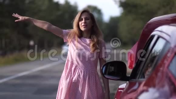 一个金发女郎站在路边靠近一辆破车那个女孩正试图阻止某人寻求帮助4K慢慢视频的预览图