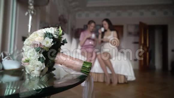 两个女孩在卧室里喝茶或咖啡婚礼早上新娘和伴娘视频的预览图