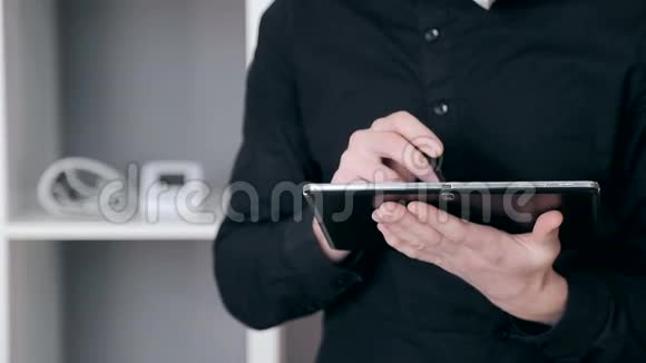 一个商人的特写镜头他手里拿着手写笔正在制作一个平板电脑视频的预览图
