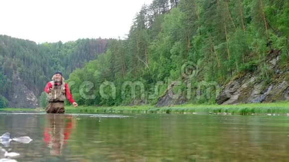 一个穿红色衣服的渔夫用鱼竿把鱼饵扔进水里去钓鱼总体计划自然动植物视频的预览图