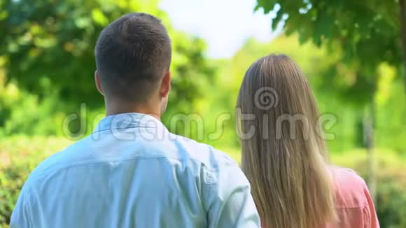 男人温柔地拥抱他的女朋友一对享受着令人惊叹的公园后景视频的预览图
