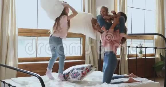 妈妈和两个可爱的女儿在床上玩枕头大战视频的预览图