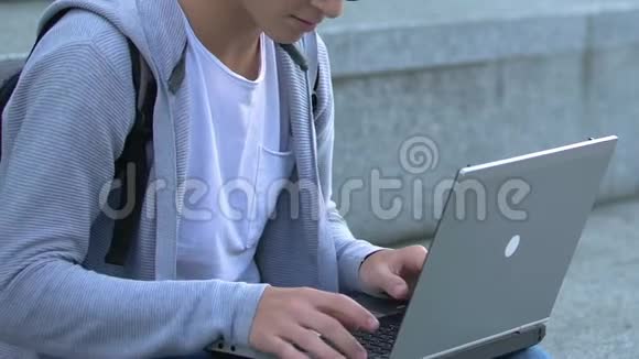 智能男性青少年在笔记本电脑户外打字作业it技术应用程序视频的预览图