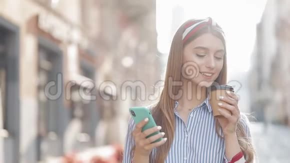 富有魅力的白种人年轻快乐女孩用她的智能手机和微笑喝咖啡散步的肖像视频的预览图