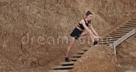 漂亮的年轻女人在木制台阶上做伸展姿势背景上有惊人的岩石视频的预览图