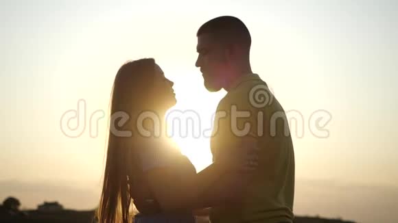 日落时分一对年轻迷人的夫妇在乡村风景中牵手接吻的剪影有胡子的年轻人视频的预览图