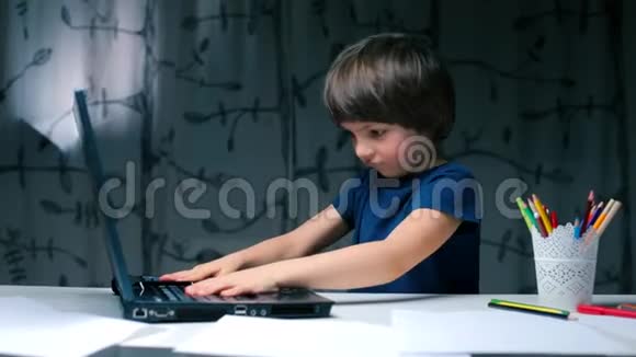 在学校里一个男孩坐在书桌前拍着笔记本电脑视频的预览图
