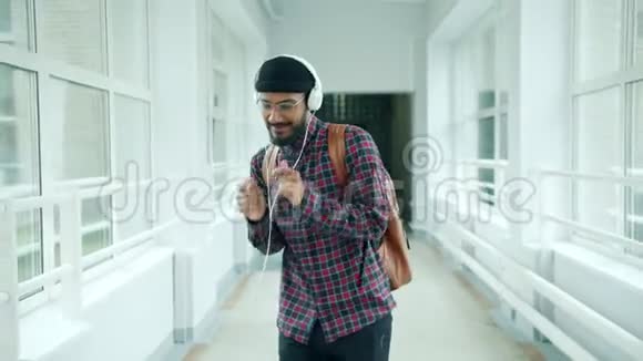 快乐的非裔美国学生在大学大厅戴着耳机跳舞玩得开心视频的预览图