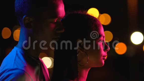 年轻的美国黑人男孩从背后拥抱女朋友欣赏城市夜景视频的预览图