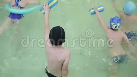 孩子们在游泳池里游泳穿着漂浮套装的孩子在学校游泳池里学习游泳视频的预览图