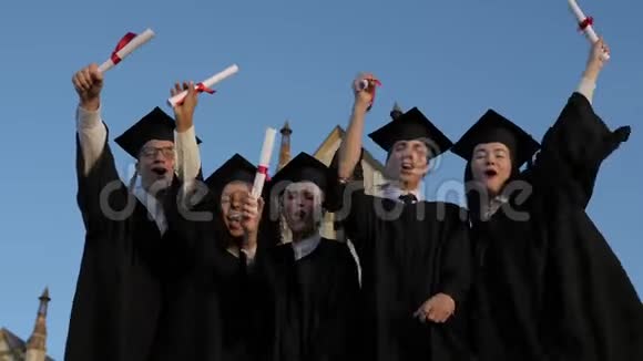 终于自由了一群穿着毕业礼服戴着硕士帽的学生站在一起举着他们的名字视频的预览图