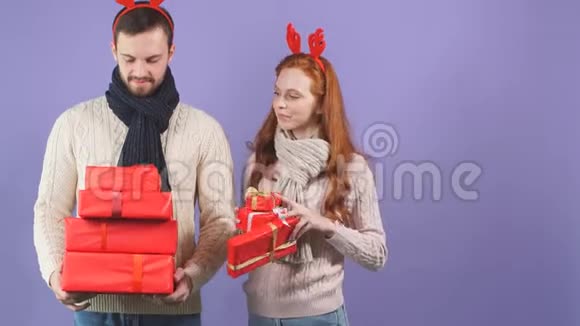 快乐的一对夫妇在工作室里戴着圣诞和新年礼物戴着红色滑稽角视频的预览图