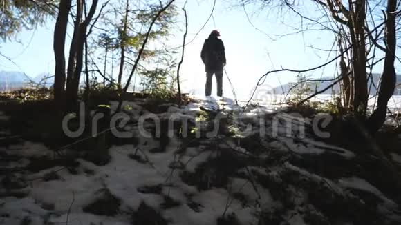 年轻的徒步旅行者在森林附近的雪地上行走在阳光明媚的日子里一个面目全非的人走在雪地上太阳光线视频的预览图