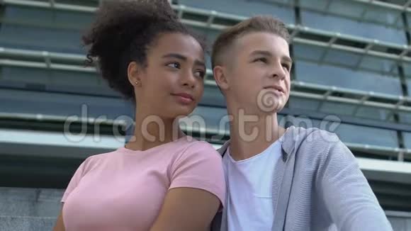 年轻的多种族青少年夫妇在学院楼梯上拥抱和享受城市景观视频的预览图