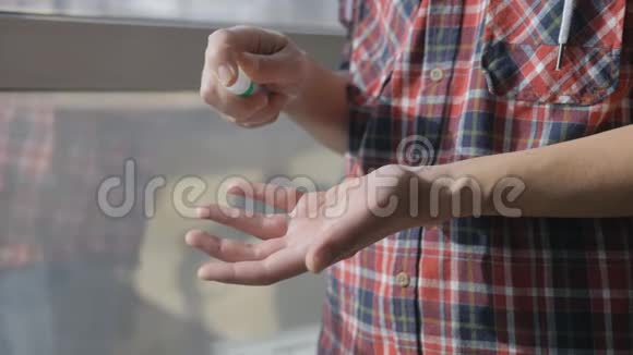 站在窗前的人正在手掌上喷洒防腐剂用于清洁双手近距离观看视频的预览图