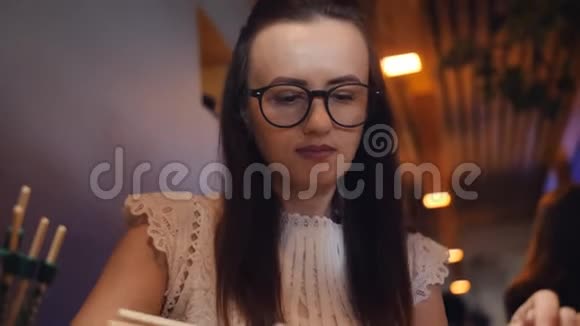 戴眼镜的女人在泛亚餐馆的筷子里吃面包卷视频的预览图