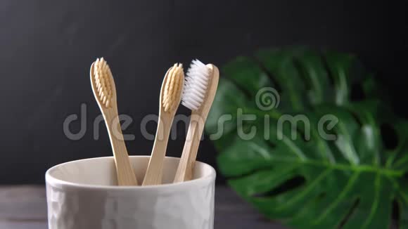 一只雄性的手把竹子牙刷放进一个白色的杯子里视频的预览图