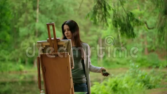 一位美丽的黑发女子在公园画一幅画的中景视频的预览图