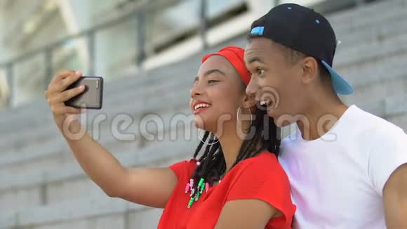 微笑非洲裔美国青少年夫妇在户外闲逛和自拍视频的预览图