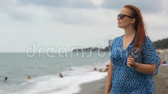 海滩上戴太阳镜和红头发的女人的肖像视频的预览图