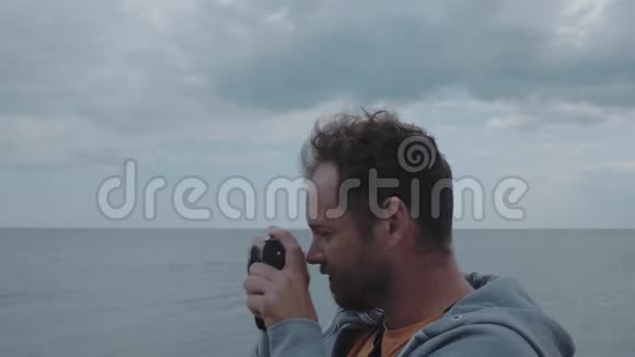 一个有胡子的人的摄影师的肖像他向取景器拍摄大海4k4k录像30英尺视频的预览图