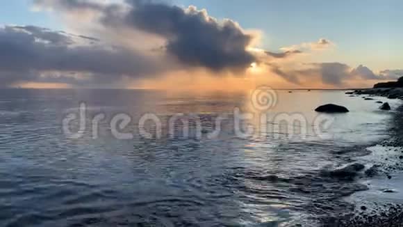 日落时的海岸如诗如画的日落宁静的水沙滩云彩被夕阳照亮视频的预览图