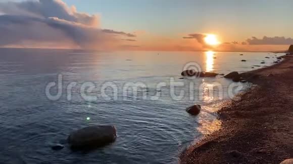 日落时的海岸如诗如画的日落宁静的水沙滩云彩被夕阳照亮视频的预览图