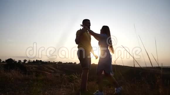 日落时分年轻迷人的夫妇在乡村风景中与天空相遇的剪影有胡子的年轻人视频的预览图