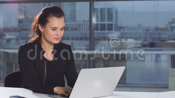 积极的美女在现代办公室用笔记本电脑工作视频的预览图