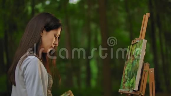 一个女孩在森林中画一幅风景画的中等肖像轮廓视频的预览图