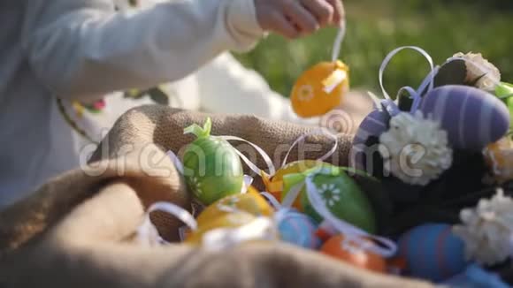女孩把散落在草地上的五颜六色的复活节彩蛋放进篮子里抚摸着毛茸茸的灰色兔子它是视频的预览图
