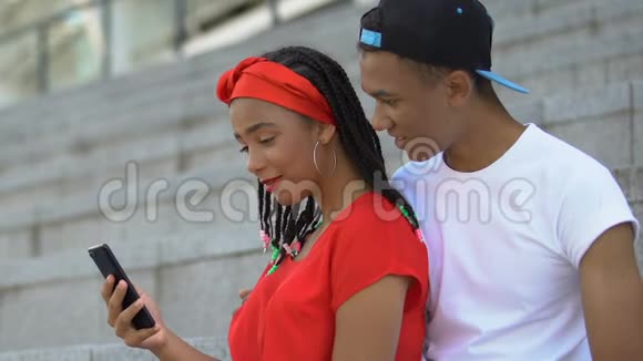 非洲裔美国青少年夫妇手持智能手机一起网购视频的预览图