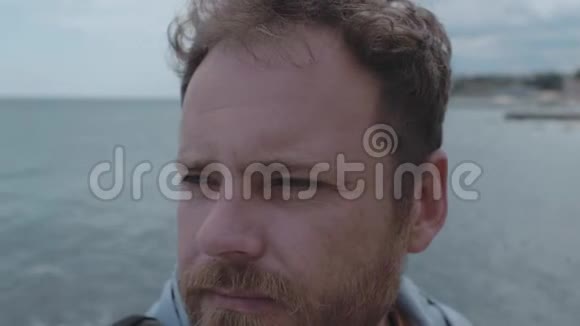 特写一个留胡子的男人的脸背景是海和云风在一个人4K中长出头发4k视频视频的预览图