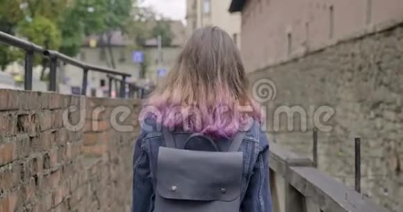 年轻女孩走在老旅游镇的老式木桥上后景视频的预览图