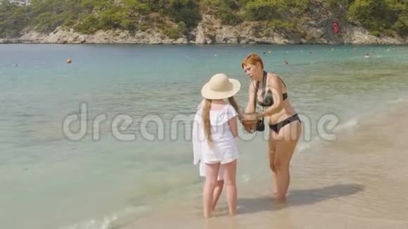 妈妈准备女儿在阳光明媚的日子在海边拍照在海边与模特合作的摄影师视频的预览图