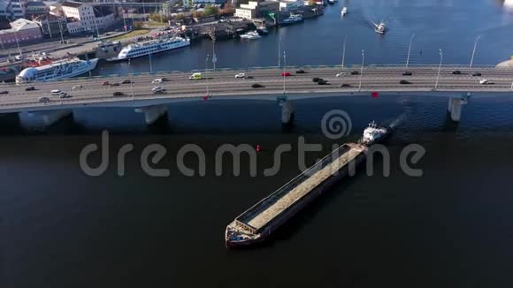 货物驳船在桥下航行桥上的城市交通视频的预览图