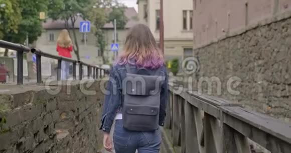 年轻女孩走在老旅游镇的老式木桥上后景视频的预览图