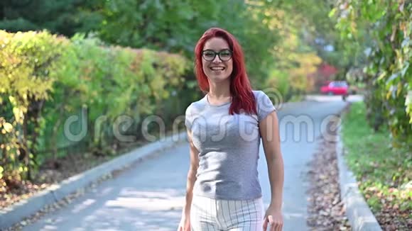 一个戴眼镜的红发美女走在街上跳舞穿灰色T恤和条纹的快乐女孩视频的预览图
