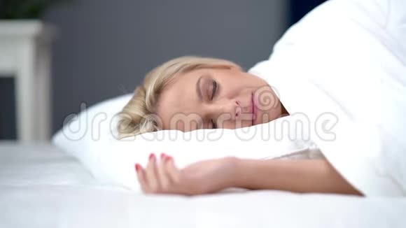 有问题的成年妇女在家中睡在白色羽绒被下视频的预览图