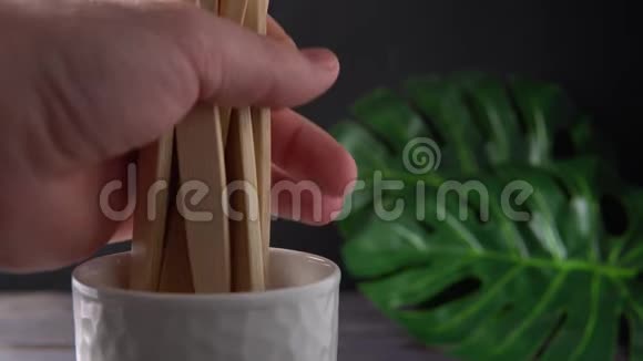 一只雄性的手把大量的竹子牙刷放在一个白色的杯子里视频的预览图