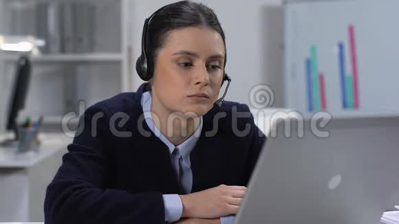 戴着耳机坐在笔记本电脑前的悲伤的年轻女人无聊的工作习惯懒惰视频的预览图