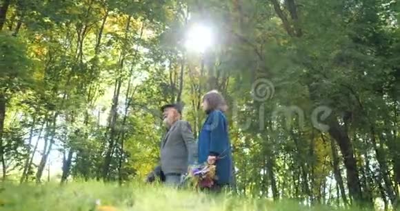 快乐的老年夫妇在秋天的公园里漫步在美丽的树木之间慢动作视频的预览图