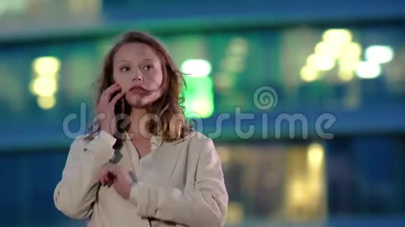担心的白种人自信的年轻商务女性穿着白色衬衫正在电话外的现代办公大楼视频的预览图