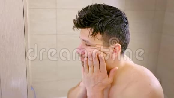 湿漉漉的男人早上在浴室的镜子里看着自己侧面看视频的预览图