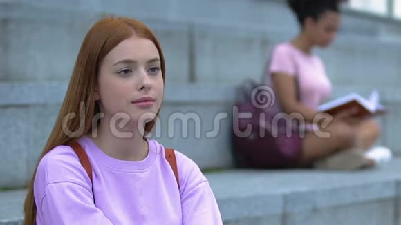 体贴的红发少女背囊坐在学院楼梯上学生视频的预览图