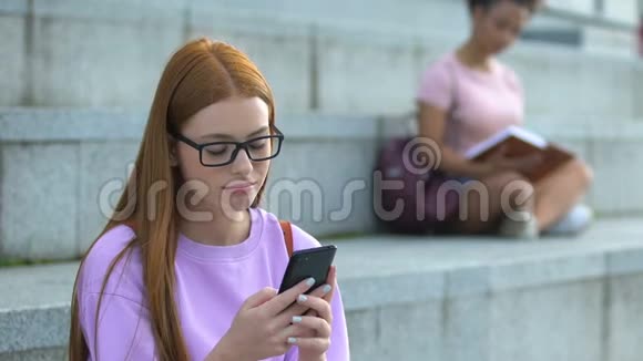 戴眼镜的高加索女青少年在手机上传递社交网络视频的预览图