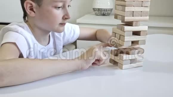 一个十几岁的白种人男孩和他的母亲一起玩木积木塔棋盘游戏因为他练习了身体和精神技能视频的预览图