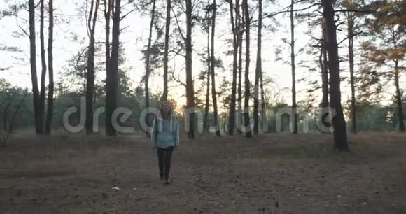 年轻的旅游旅行者穿着蓝色夹克背着旅游背包在秋天的森林里散步享受秋天的夜晚视频的预览图