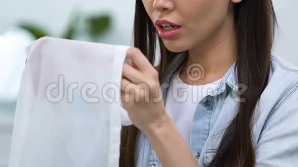 不满意的女孩展示衬衫上有咖啡污渍洗衣问题视频的预览图